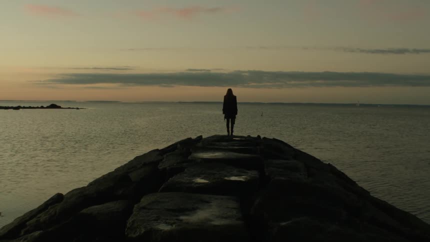 Woman standing on a cliff overlooking water