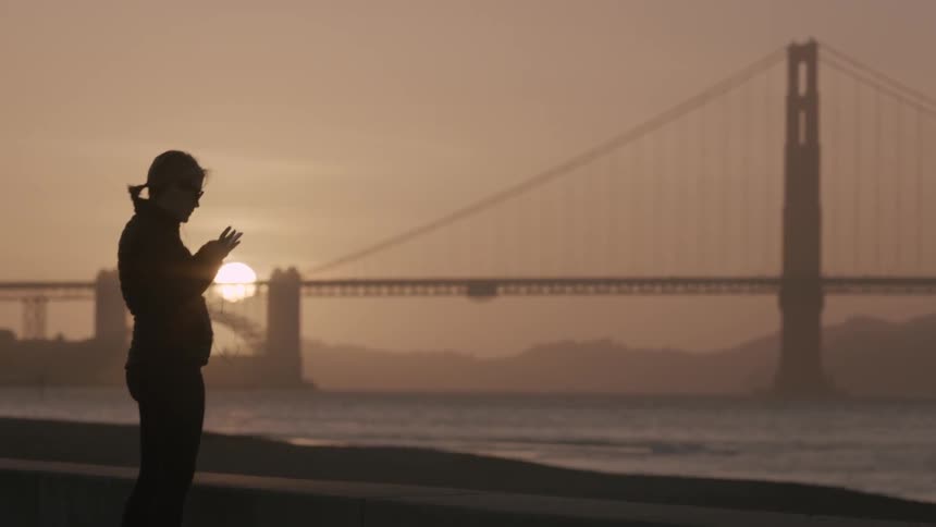 A person stands on the shore at sunset