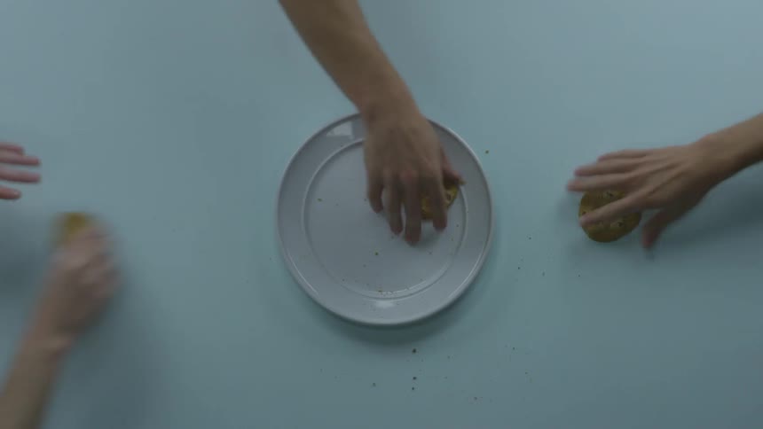Hungry young people snatch away homemade cookies from a white plate