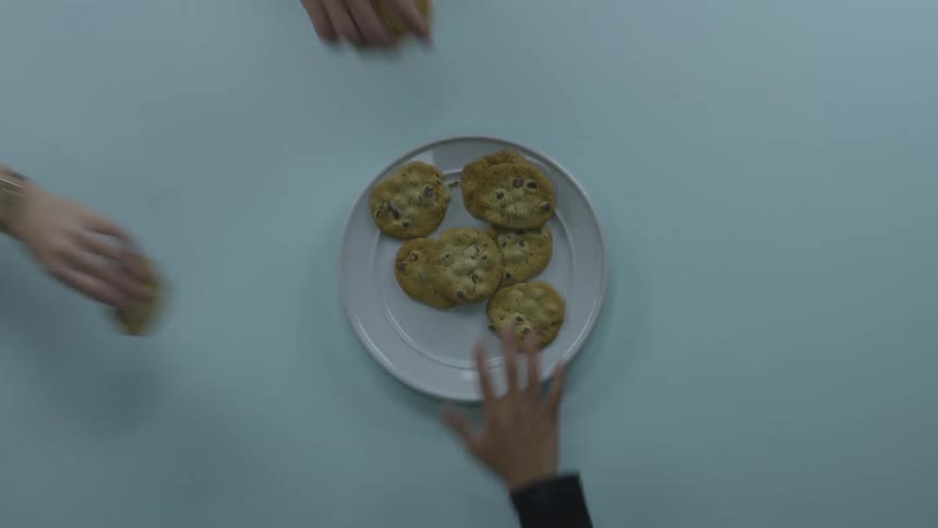 Hands reach for cookies on a plate
