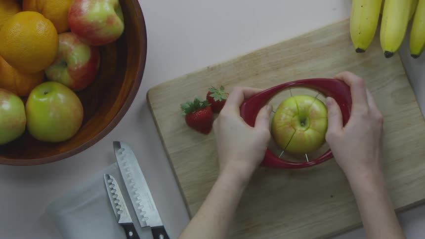 Someone slices an apple with an apple slicer