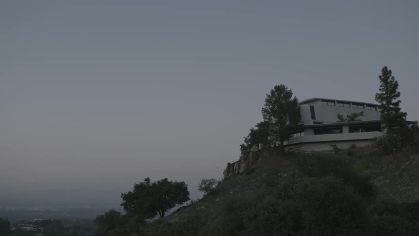 A large white house sits on a cliff on a cloudy day