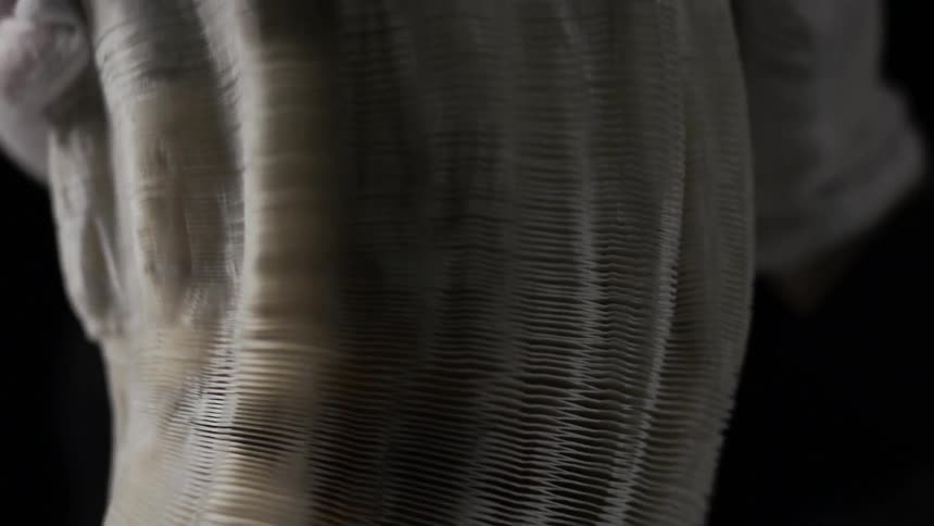 A white statue slowly forms in a dark area