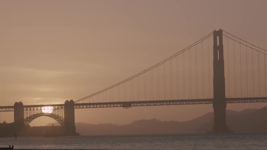 The golden gate bridge with the sun rising/setting in the background