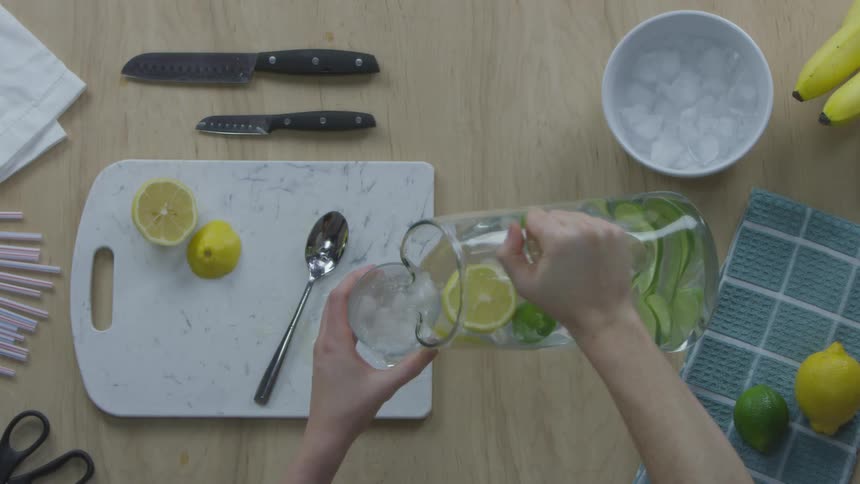 Person pouring lemon lime water in a glass