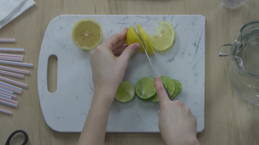 A person cuts lemon slices on a cutting board