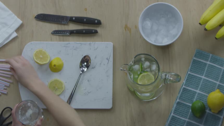 Woman fills lemonade into glass then puts pipette on top of lemonade in the kitchen