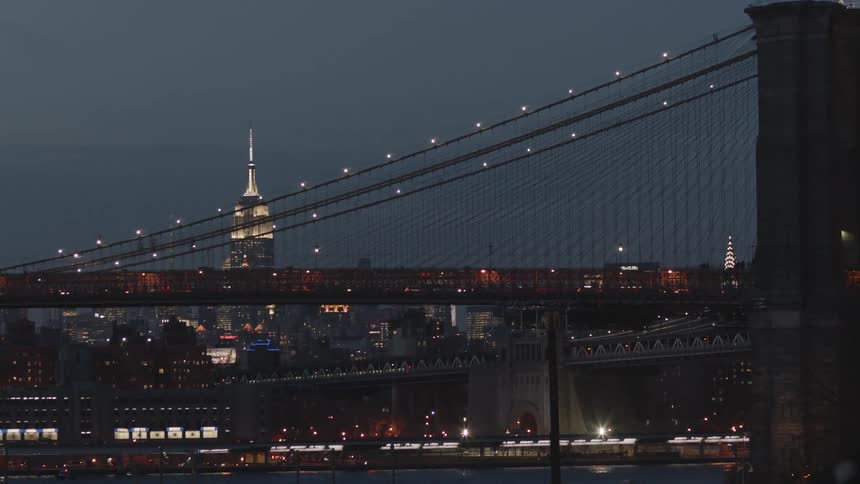 A view of a city at night focusing on traffic going over a bridge in the distance