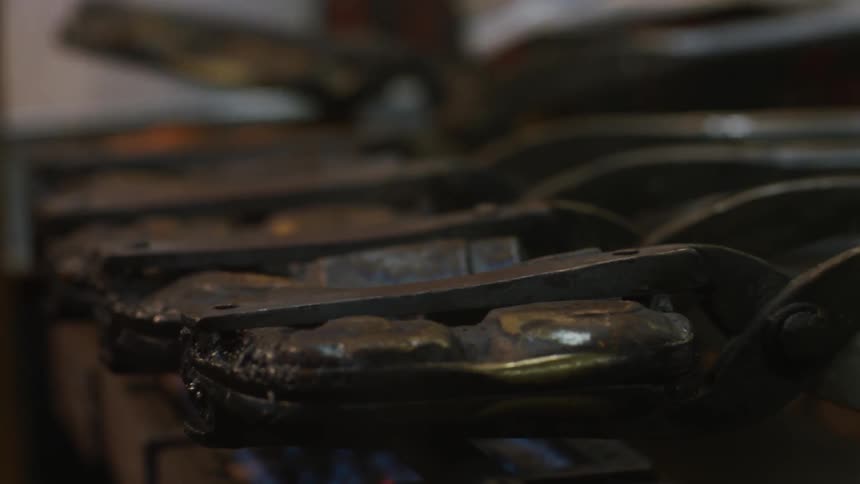 Metal griddles are being flipped on a hot stove