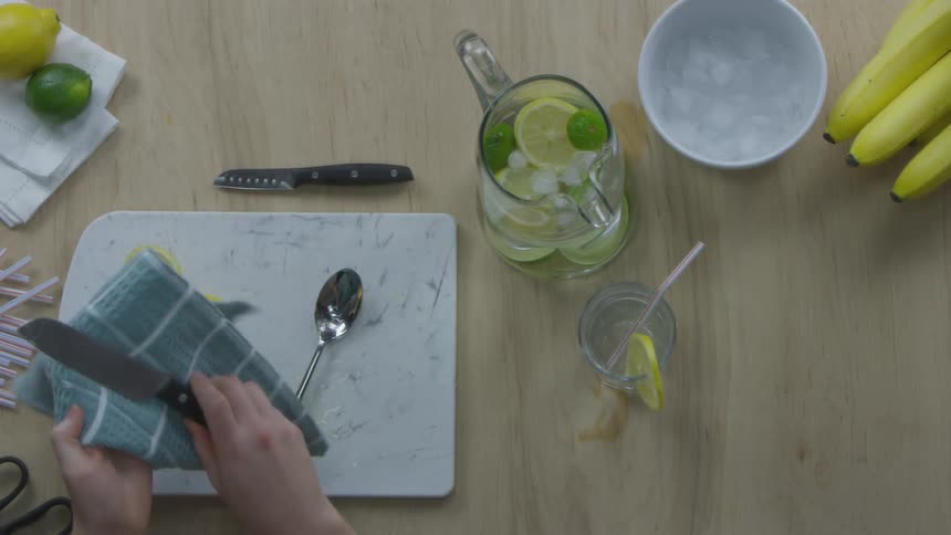 A person wipes knives on a kitchen towel after making lemonade
