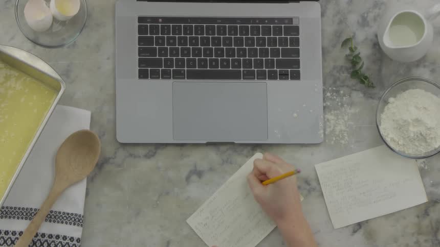 Woman uses laptop then takes notes on the marble table by day