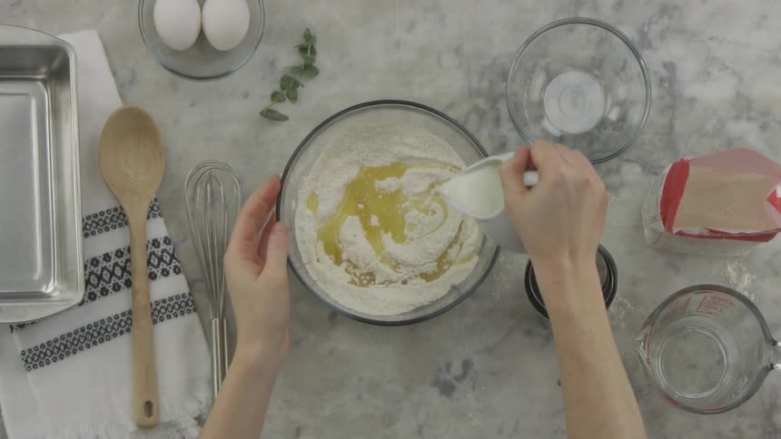 Woman adds milk to flour mixture