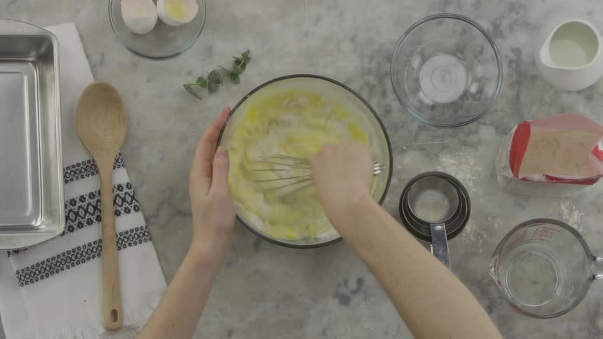 Eggs are added to a glass bowl and whisked into other ingredients in a kitchen
