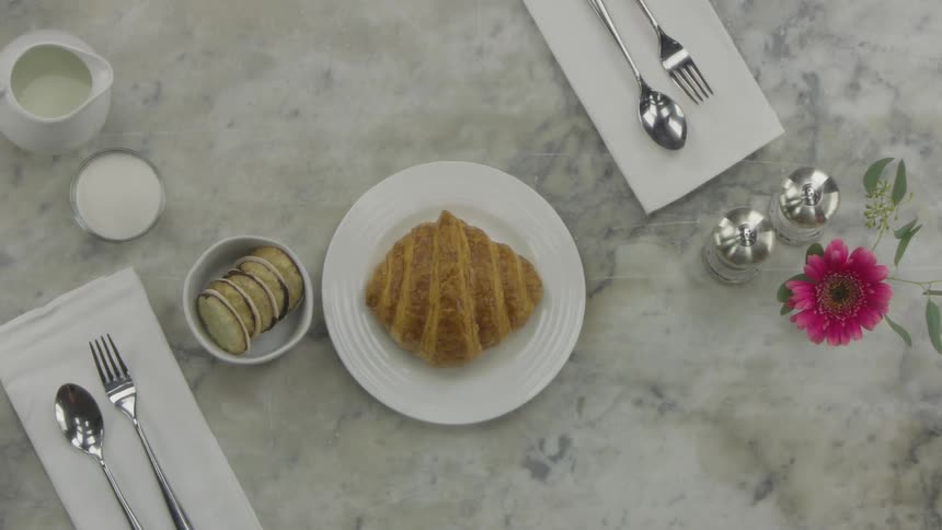Setting the breakfast table with a pastry and two cups of coffee