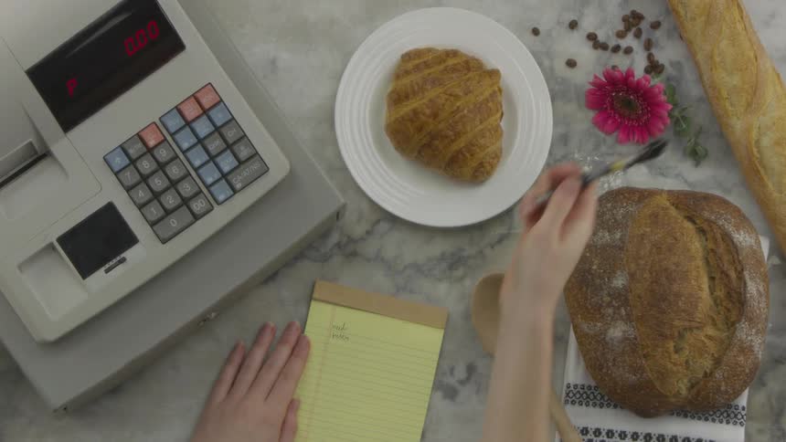Woman takes notes next to the cash register on the marble table by day