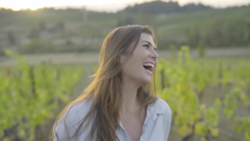 A woman laughing in the middle of a vineyard