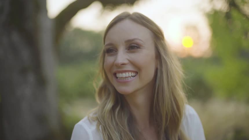 Blonde woman laughs and talk in the forest at sunset