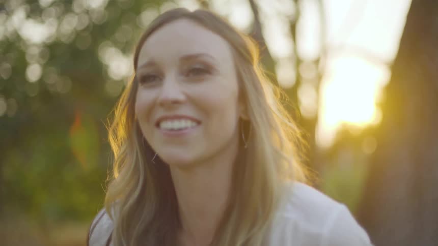 Woman with long hair laughing and talking on sunny day in nature