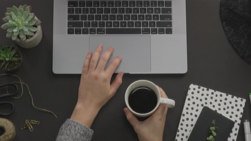 A person using a laptop and drinking coffee