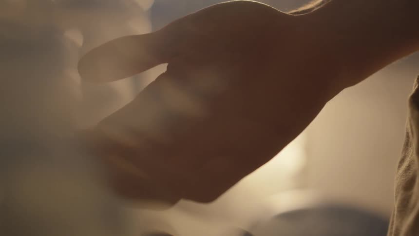 A man holds his hand palm up in sunlight coming in through a window