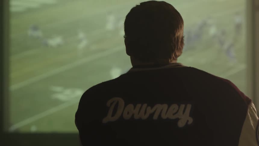 A man watches a screen which is displaying a football game