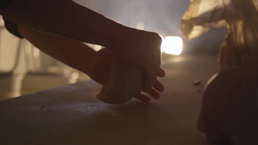 Person molds clay against a table