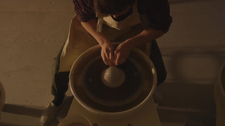 A man sits and makes pottery