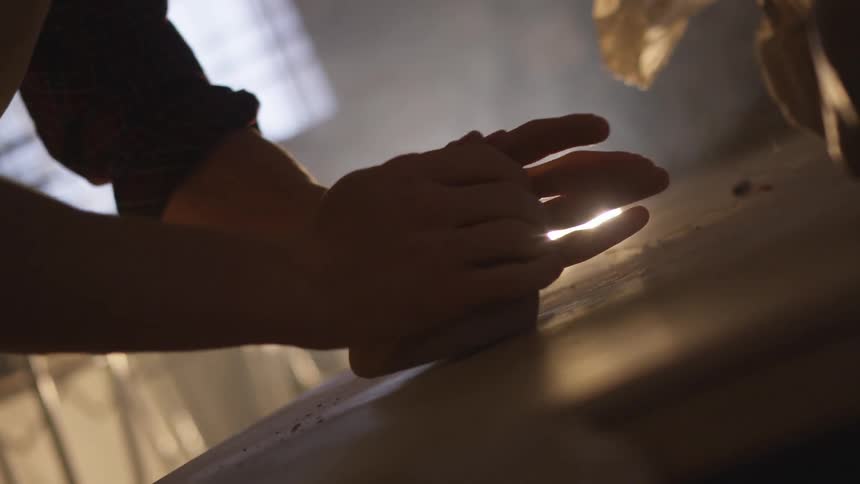 A white person kneads dough on a wooden counter in a kitchen