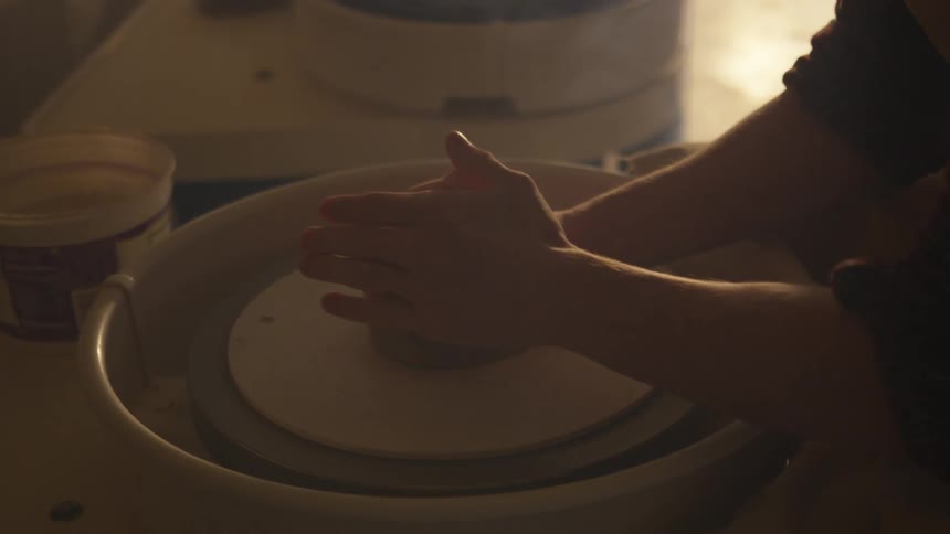 A person sculpting clay on a pottery wheel