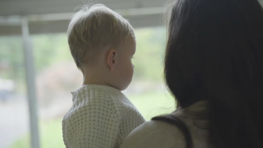 Mother talking to toddler while looking out the window