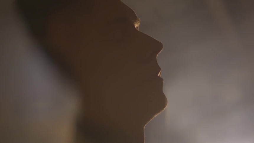 A light shines behind a mans face indoors