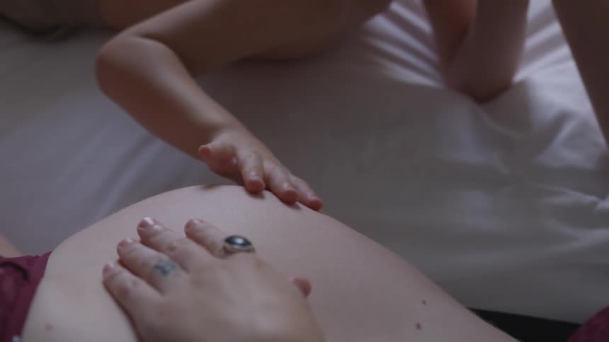 A boy is touching a pregnant woman's stomach