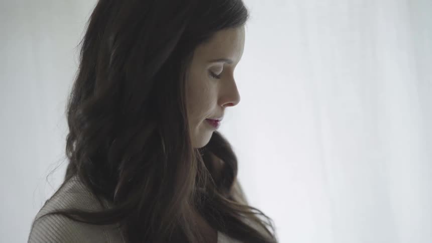 Woman stands with eyes closed