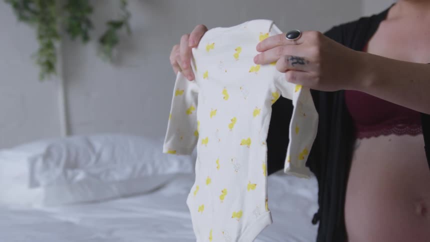 A pregnant woman folding baby clothes