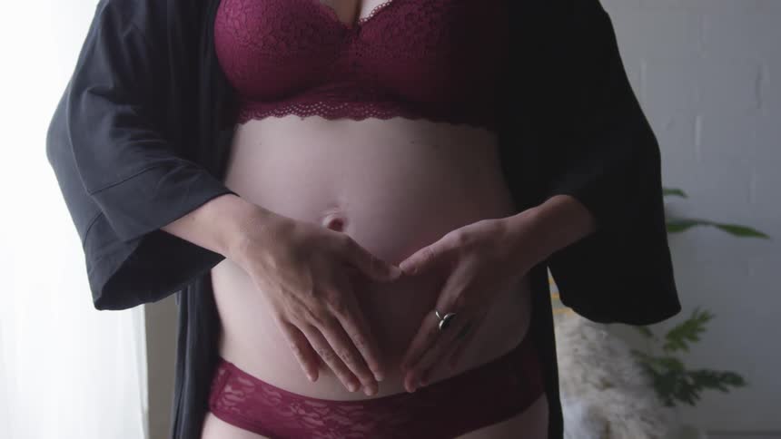 Pregnant woman in lingerie hearts stomach