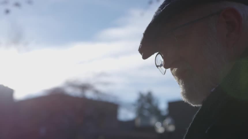 An older man wearing glasses looking downward