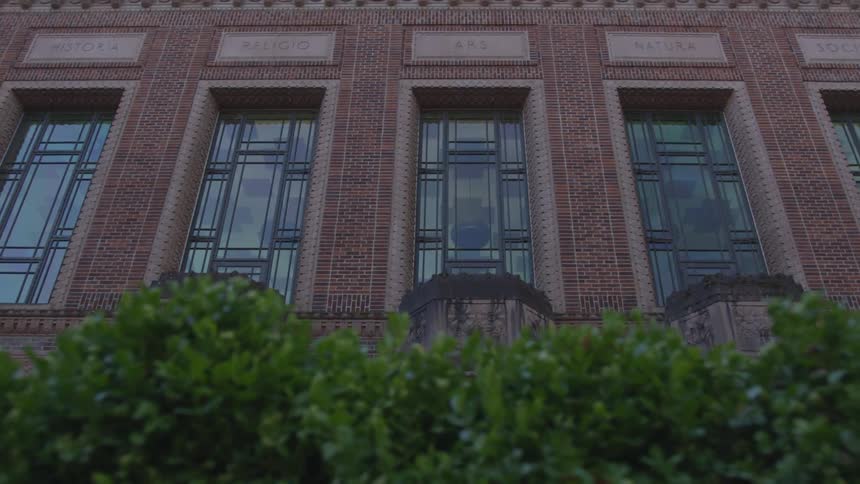 Looking at a tall building with a hedge in front of it