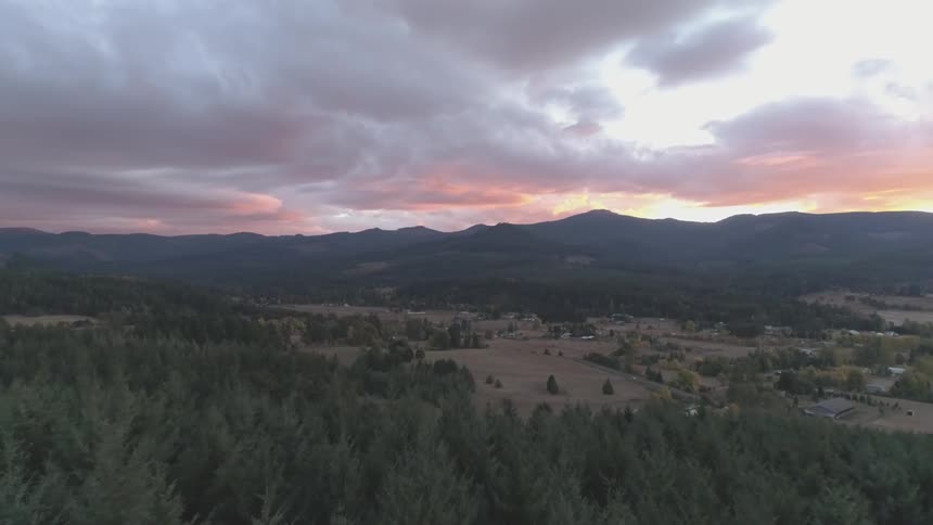 An aerial view of a rural area surrounded by mountains at sunset