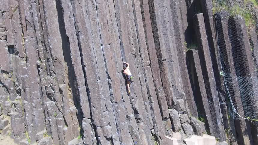 Man climbs up the side of a cliff