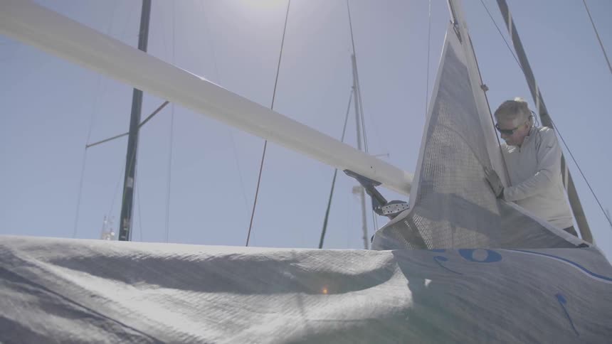 Man inspects the sail on a boat