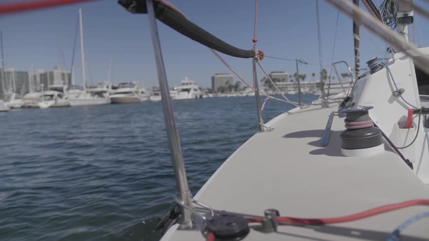 A yacht sails toward a marina and shore with large hotels and palm trees