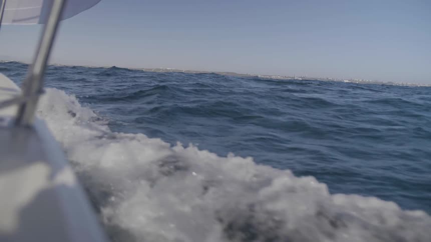Boat cruising through choppy water in the ocean on a clear day