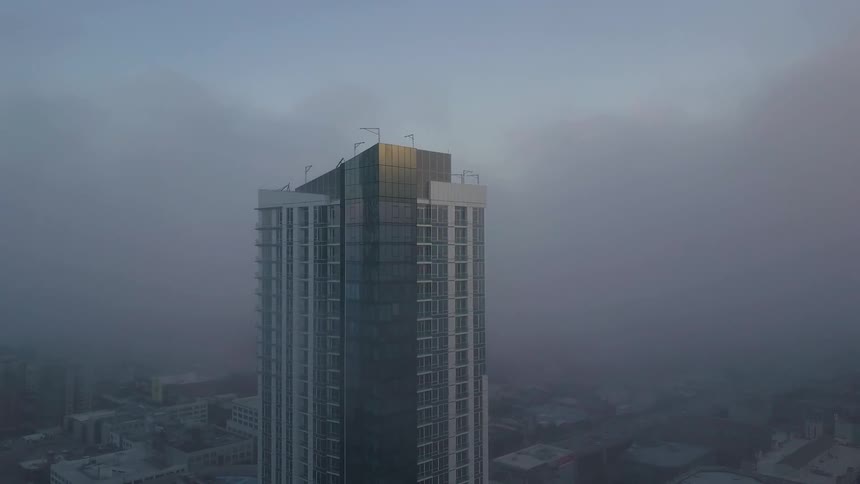 A large building with a lot of clouds rolling in behind it