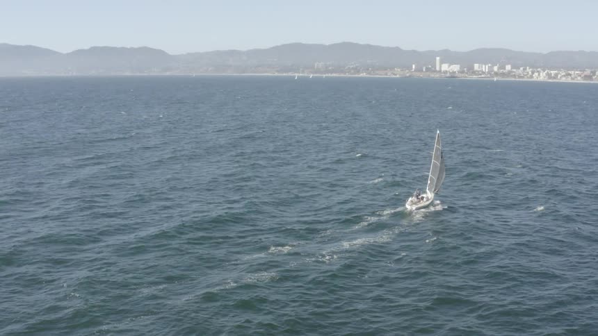 Boat sails towards the shore at sea on a sunny day