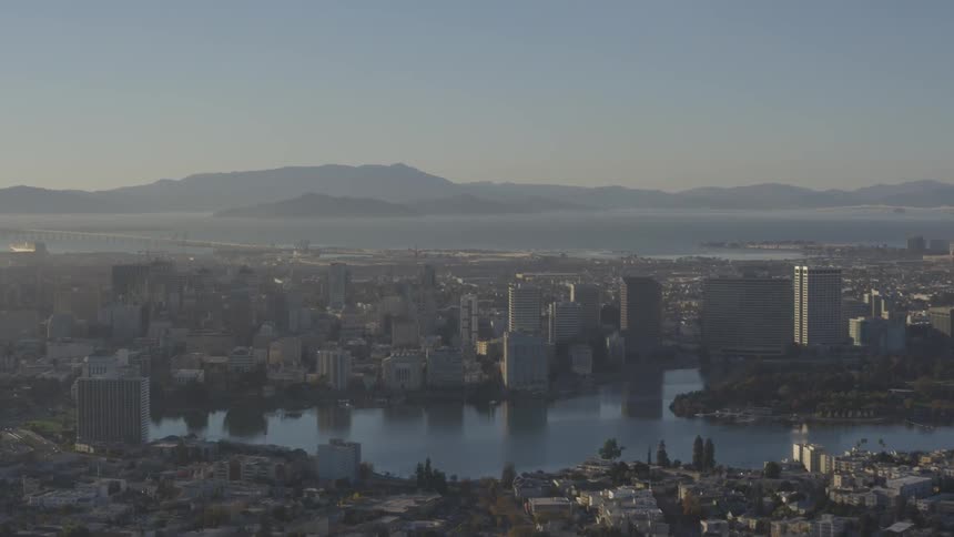 Cityscape surrounds water with mountain on horizon