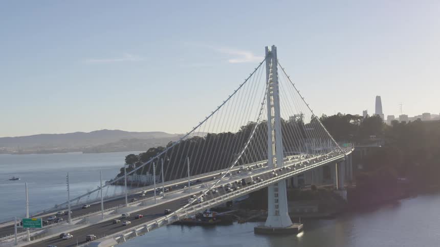Traffic crosses toward city over suspension bridge