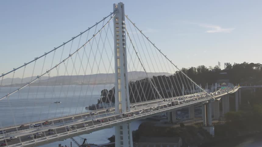 Cars drive over a river on a large wire city bridge