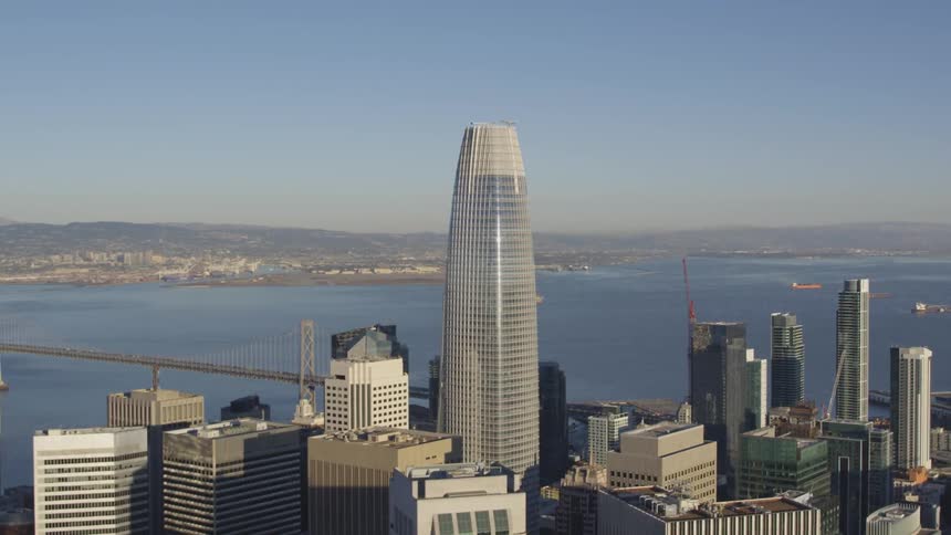 Skyscraper towers above many other buildings by a river