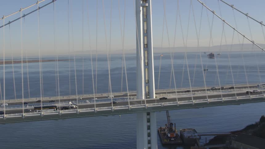 Cars cross suspension bridge over ocean