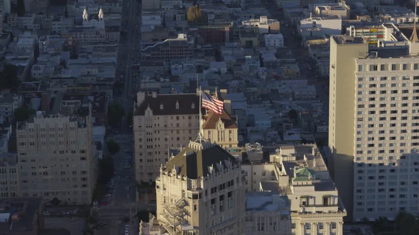 An american flag waving in the wind atop a building a city